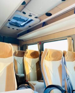 Modern minibus interior with beige seats, overhead storage, and skylight for natural light
