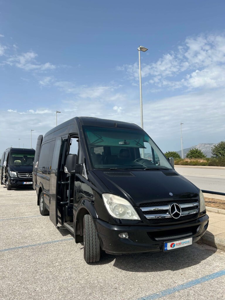 Black Mercedes minibuses parked in a row under a partly cloudy sky, front door open